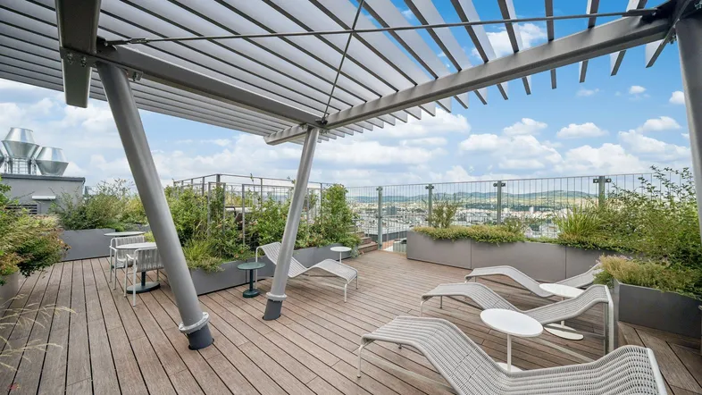 Geräumige Dachterrasse mit modernen Liegestühlen, Pergola und weitem Stadtblick.