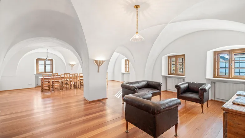 Geräumiger Wohnbereich mit eleganten Gewölbedecken, Holzboden und bequemen Ledersofas.