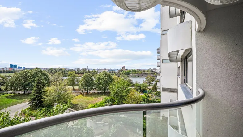 Geräumiger Balkon mit Glasbrüstung, Blick auf den Fluss und die grüne Umgebung.