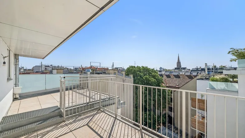Geräumige Dachterrasse mit hellem Fliesenboden und weitem Blick über die Stadt.