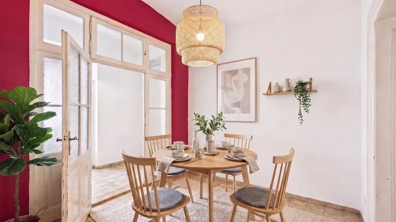Helles Esszimmer mit Holztisch, Stühlen und auffälliger roter Wandfarbe, modern eingerichtet.