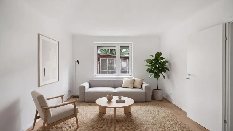 Helles Wohnzimmer mit modernem Sofa, Holztisch und Blick ins Grüne durch das Fenster.