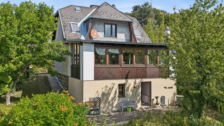Charmantes Einfamilienhaus mit Wintergarten und Mansarddach in grüner Umgebung.