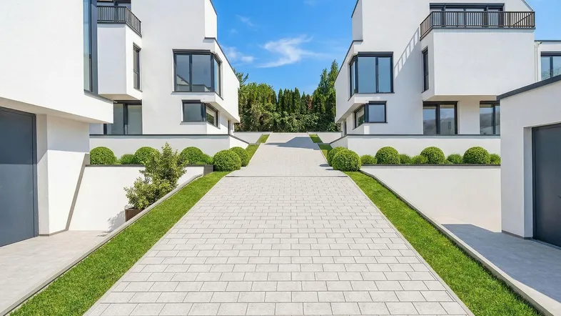 Moderne weiße Villen mit klaren Linien und gepflegter Zufahrt unter blauem Himmel.