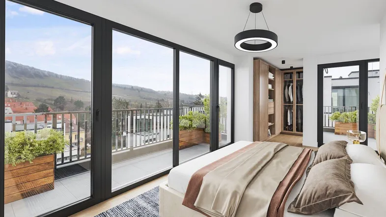 Helles Schlafzimmer mit großen Fenstern, Zugang zum Balkon und Blick auf die umliegende Landschaft.