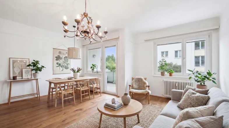 Helles Wohn- und Esszimmer mit Holzboden, modernen Möbeln und Zugang zum Balkon.