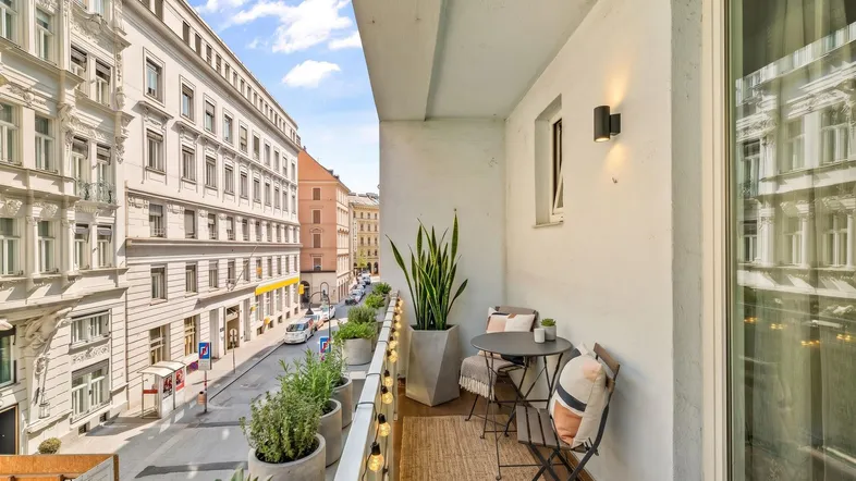 Möblierter Balkon mit Pflanzen und Blick auf die belebte Stadtstraße.
