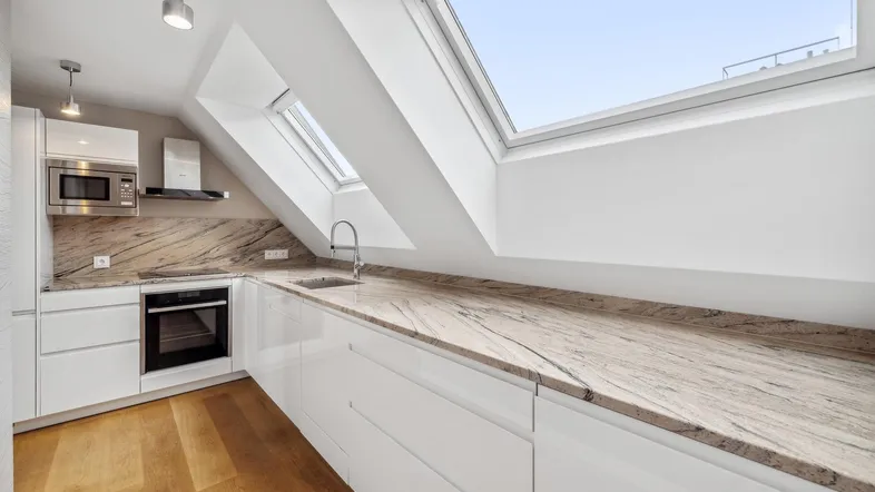 Moderne Küche im Dachgeschoss mit weißen Hochglanzfronten, Granitarbeitsplatte und Dachfenstern.