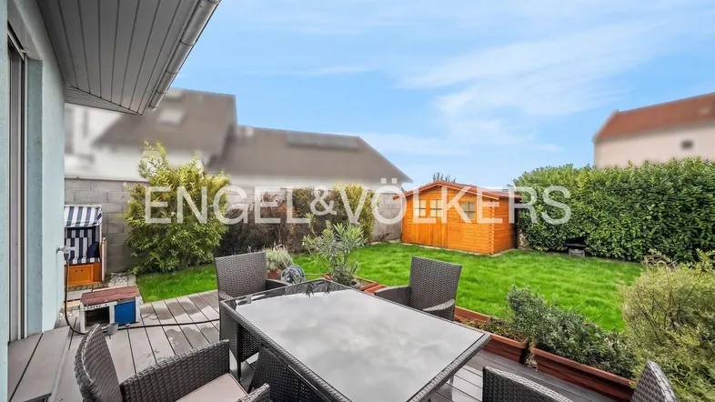 Gemütliche Terrasse mit Gartenmöbeln und Blick auf den gepflegten Rasen und Gartenschuppen.