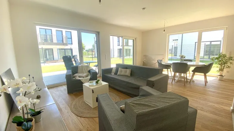 Helles Wohn- und Esszimmer mit Holzboden, großen Fenstern und Zugang zur Terrasse.