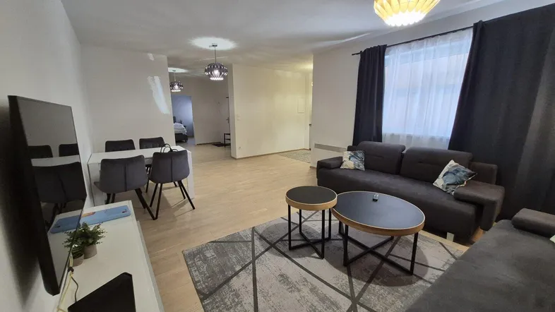 Geräumiger Wohn- und Essbereich mit modernem Sofa, Couchtischen und hellem Holzboden.