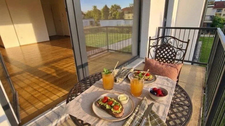 Gemütlicher Balkon mit Frühstückstisch und Blick ins Grüne, ideal für sonnige Morgenstunden.
