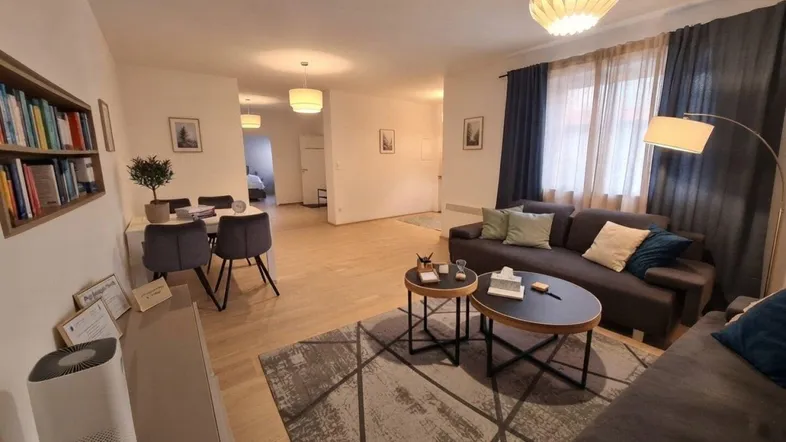 Geräumiger Wohn- und Essbereich mit bequemen Sofas, Esstisch und Bücherregal, ideal für geselliges Beisammensein.