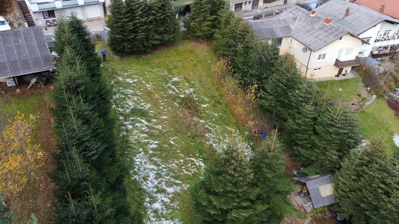 Luftaufnahme eines Grundstücks mit Bäumen und umliegenden Häusern, teilweise mit Schnee bedeckt.