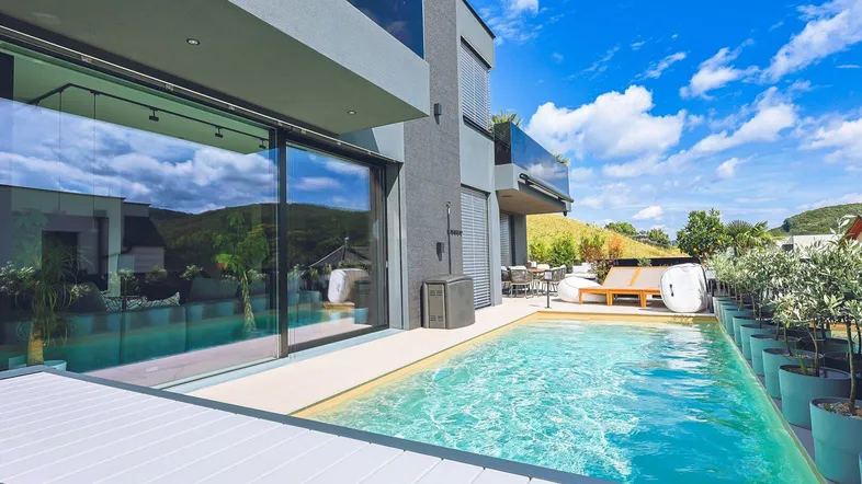 Moderner Außenbereich mit Infinity-Pool, Liegeflächen und Blick auf die umliegende Landschaft.