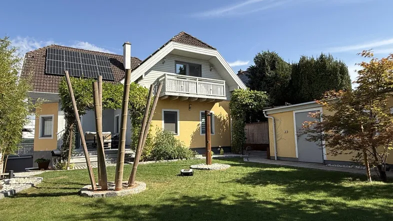 Großzügiger Gartenbereich mit gepflegtem Rasen, Bäumen und Solaranlage auf dem Dach des Hauses.