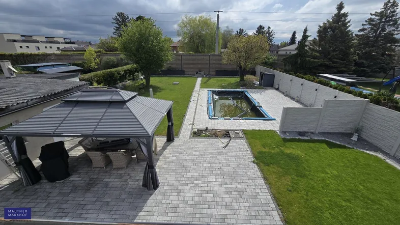 Weitläufiger Gartenbereich mit Pool, überdachtem Sitzbereich und gepflegter Rasenfläche.