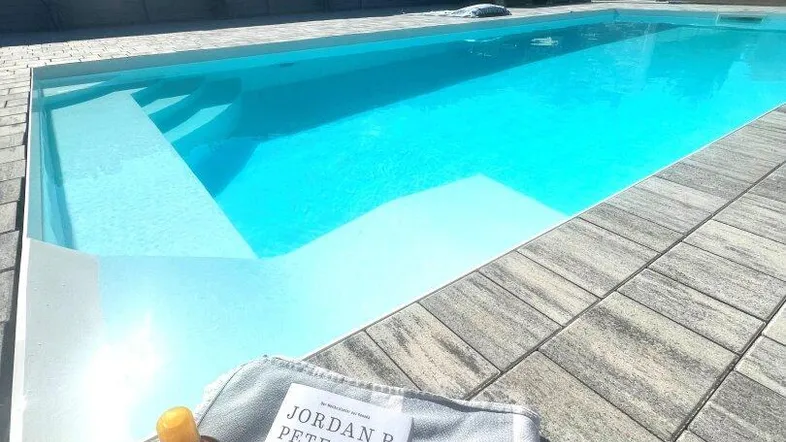 Entspannender Poolbereich mit klarem Wasser, Liegefläche und sonnigem Ambiente.