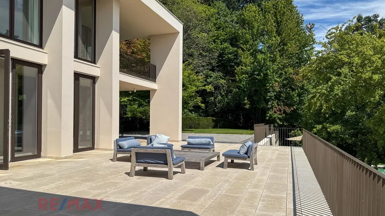 Große, sonnige Terrasse mit modernen Loungemöbeln und Blick ins Grüne.