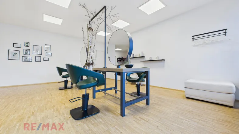 Heller und moderner Friseursalon mit mehreren Bedienplätzen, großen Spiegeln und Holzfußboden.