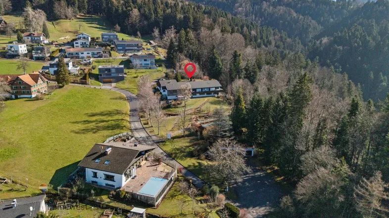 Luftaufnahme eines Anwesens mit Pool und umliegender grüner Landschaft, umgeben von Wald.