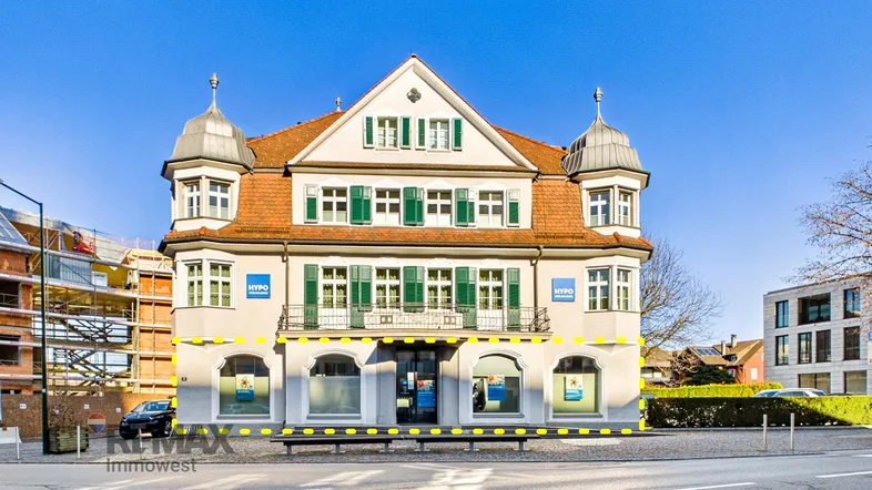 Historisches Gebäude mit traditioneller Architektur, grünen Fensterläden und einem kleinen Balkon an der Fassade.