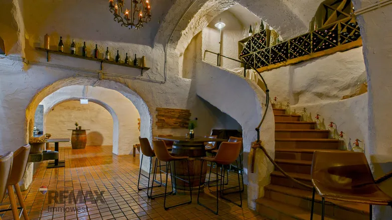 Historischer Weinkeller mit Gewölbedecken, Wendeltreppe und gemütlichen Sitzbereichen für Gäste.