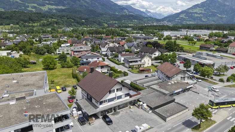Luftaufnahme des Anwesens mit umliegender Wohnbebauung und beeindruckendem Bergpanorama im Hintergrund.