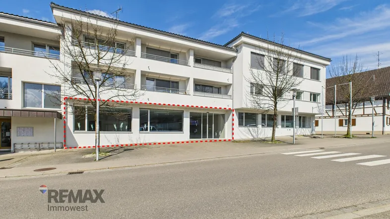 Außenansicht des Geschäftsgebäudes mit großen Schaufenstern und einer roten Umrandung des Mietbereichs.