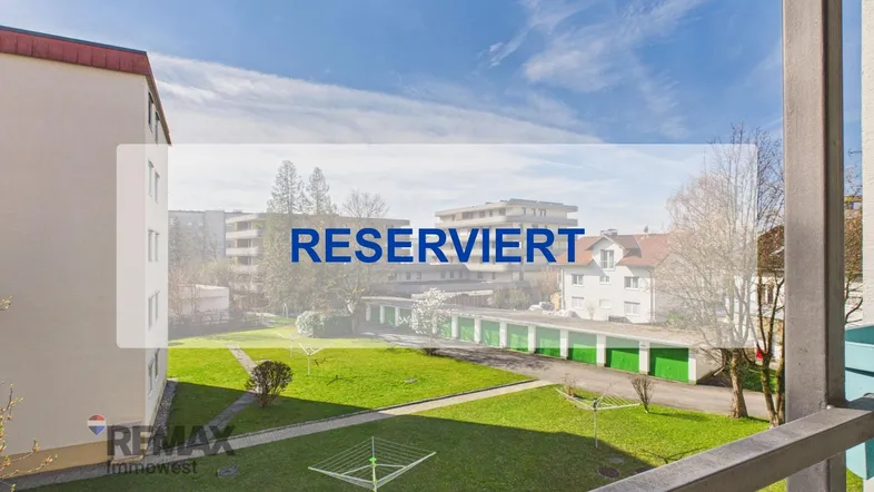 Blick vom Balkon auf die grüne Wohnanlage mit Garagen und umliegenden Gebäuden.