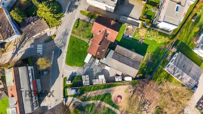 Luftaufnahme eines Wohngebiets mit Häusern, Gärten und Straßen in sonniger Umgebung.