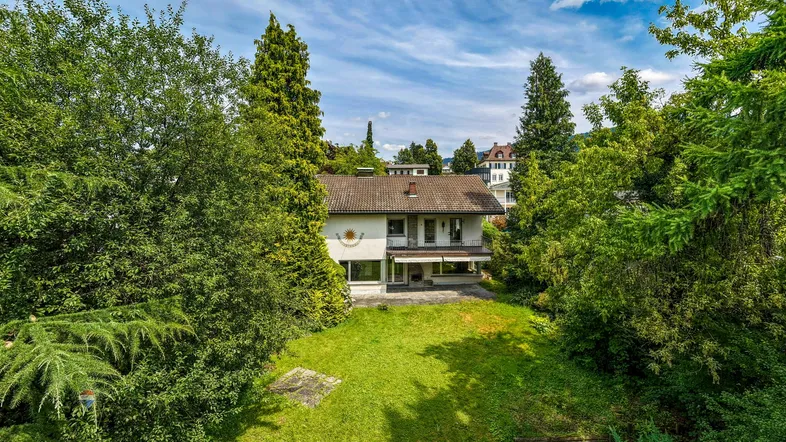 Großzügiger Gartenbereich mit Rasenfläche und altem Baumbestand vor dem Einfamilienhaus.