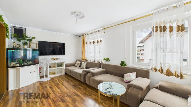 Helles Wohnzimmer mit großem Sofa, Holzboden und Aquarium, ideal für entspannte Stunden.