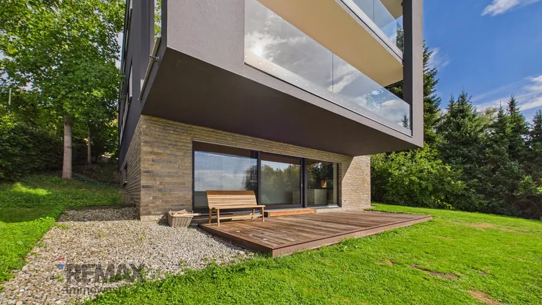Moderne Architektur mit Holzterrasse und Gartenbereich in sonniger Lage.