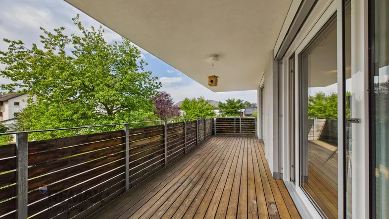 Geräumiger Balkon mit Holzboden und Blick ins Grüne, ideal für entspannte Stunden im Freien.