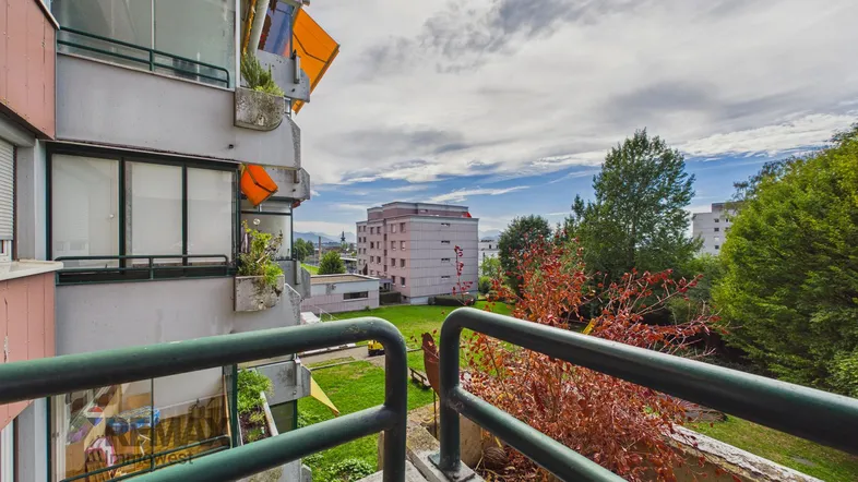 Blick vom Balkon auf die umliegenden Gebäude und Grünflächen mit weitem Ausblick.