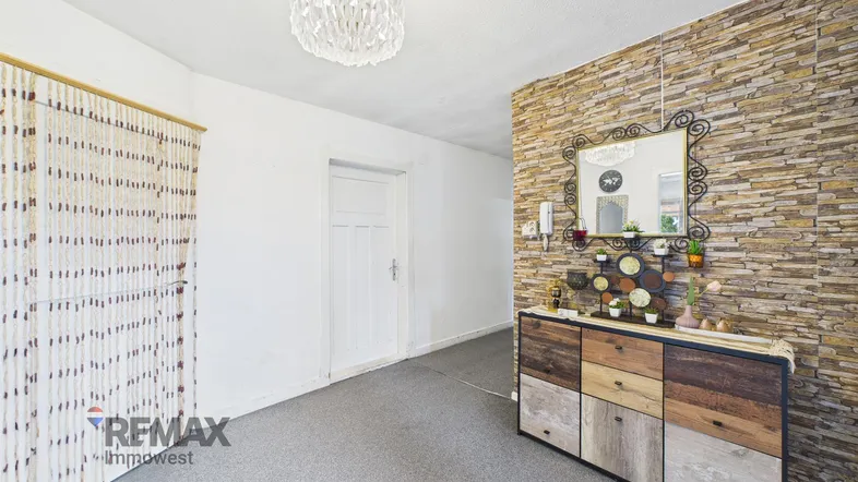 Heller Flur mit Steinwand-Akzent, dekorativer Kommode und moderner Deckenleuchte.