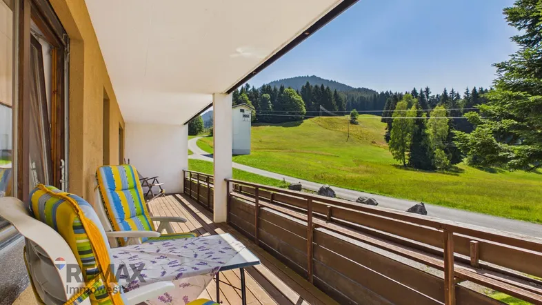 Geräumiger Balkon mit Sitzgelegenheiten und weitem Blick auf die umliegende grüne Landschaft.