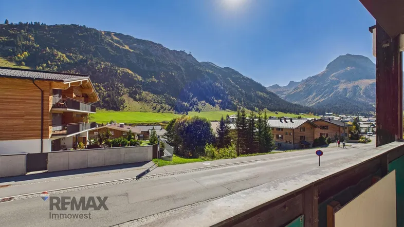 Sonnige Aussicht auf die umliegende Berglandschaft und die Straße von einem Balkon.