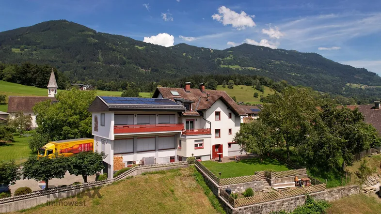 Luftaufnahme des Anwesens mit Bergen im Hintergrund und Solaranlage auf dem Dach.
