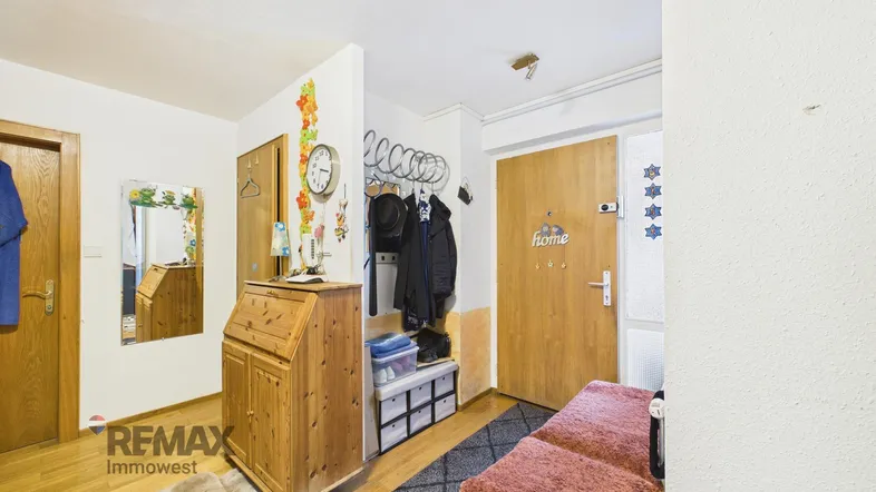 Heller Eingangsbereich mit Garderobe, Holzmöbeln und einem Spiegel.