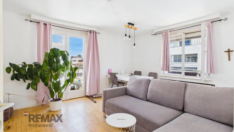 Helles Wohnzimmer mit Sofa, Esstisch und Zugang zu einem französischen Balkon.