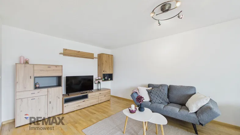 Helles Wohnzimmer mit Holzfußboden, modernem Sofa und Medieneinheit aus hellem Holz.