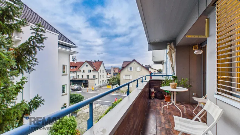 Gemütlicher Balkon mit Holzboden, Sitzgelegenheiten und Blick auf die umliegende Wohngegend.