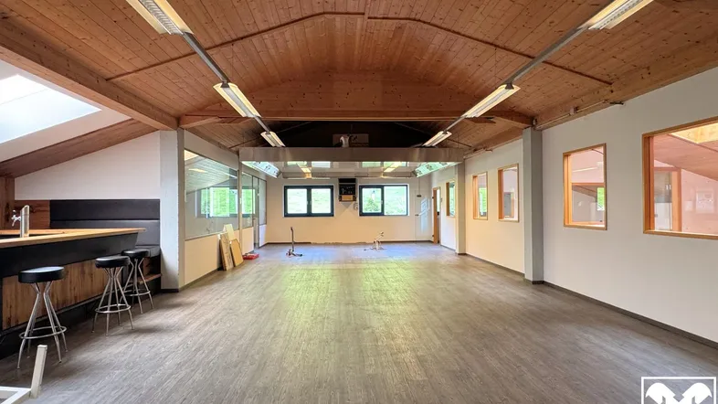 Großer, offener Raum mit Holzbalkendecke und moderner Bar, ideal für Veranstaltungen oder Büros.