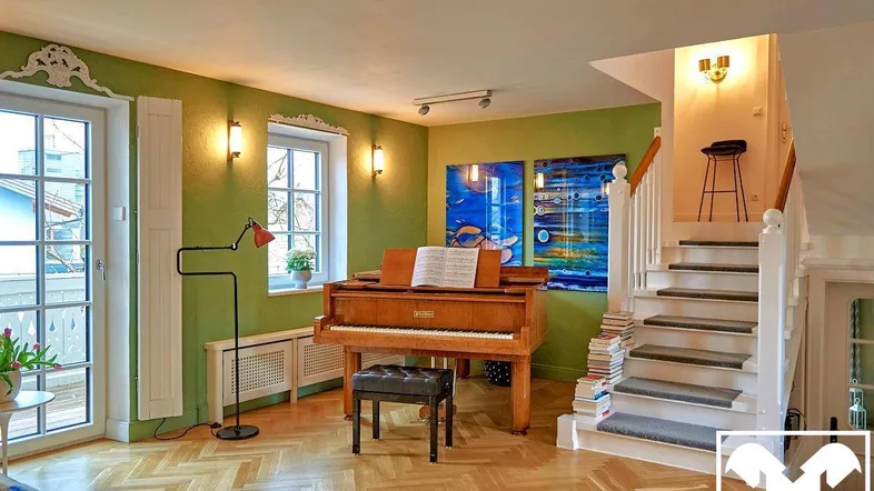 Helles Wohnzimmer mit Parkettboden, Klavier und Zugang zu einem Balkon.