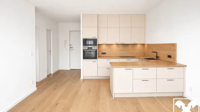 Moderne Einbauküche in hellem Beige mit Holzakzenten und Parkettboden in einem offenen Wohnbereich.