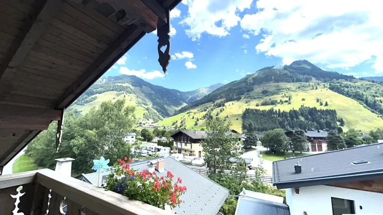 Traditioneller Holzbalkon mit Blumenkästen und weitem Blick auf die umliegende Berglandschaft.