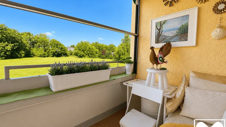 Heller Balkon mit Markise, Sitzgelegenheit und weitem Blick ins Grüne.
