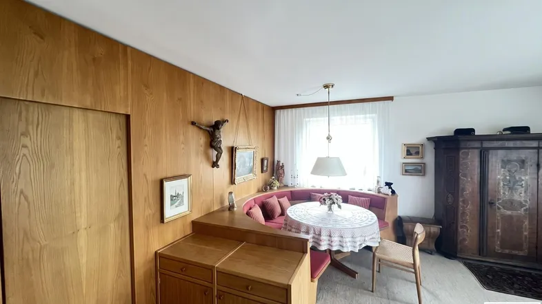 Gemütlicher Wohn-Essbereich mit traditioneller Holztäfelung, Eckbank und Blick ins Grüne.